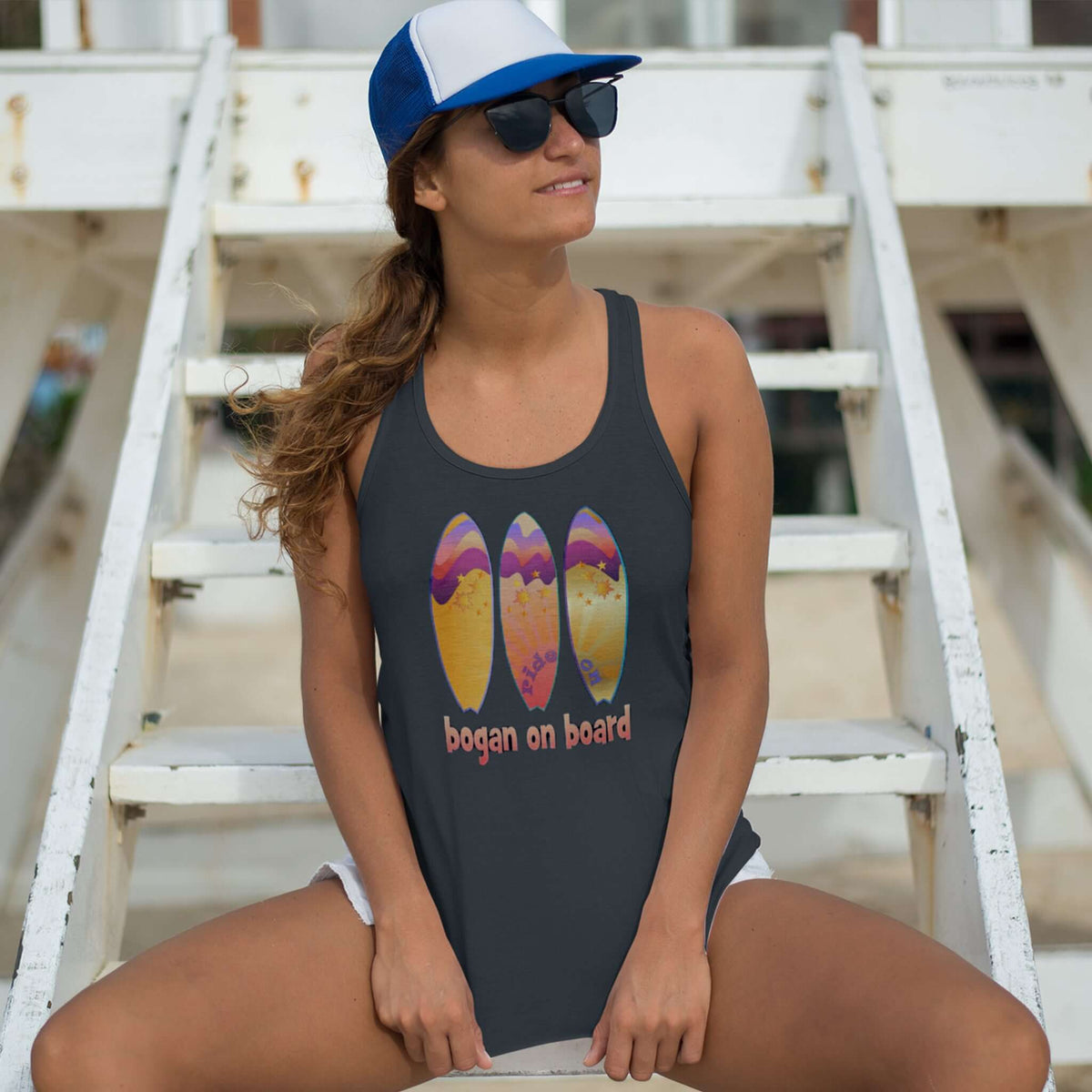 Model at beach wears black tank top wth Australian surf design