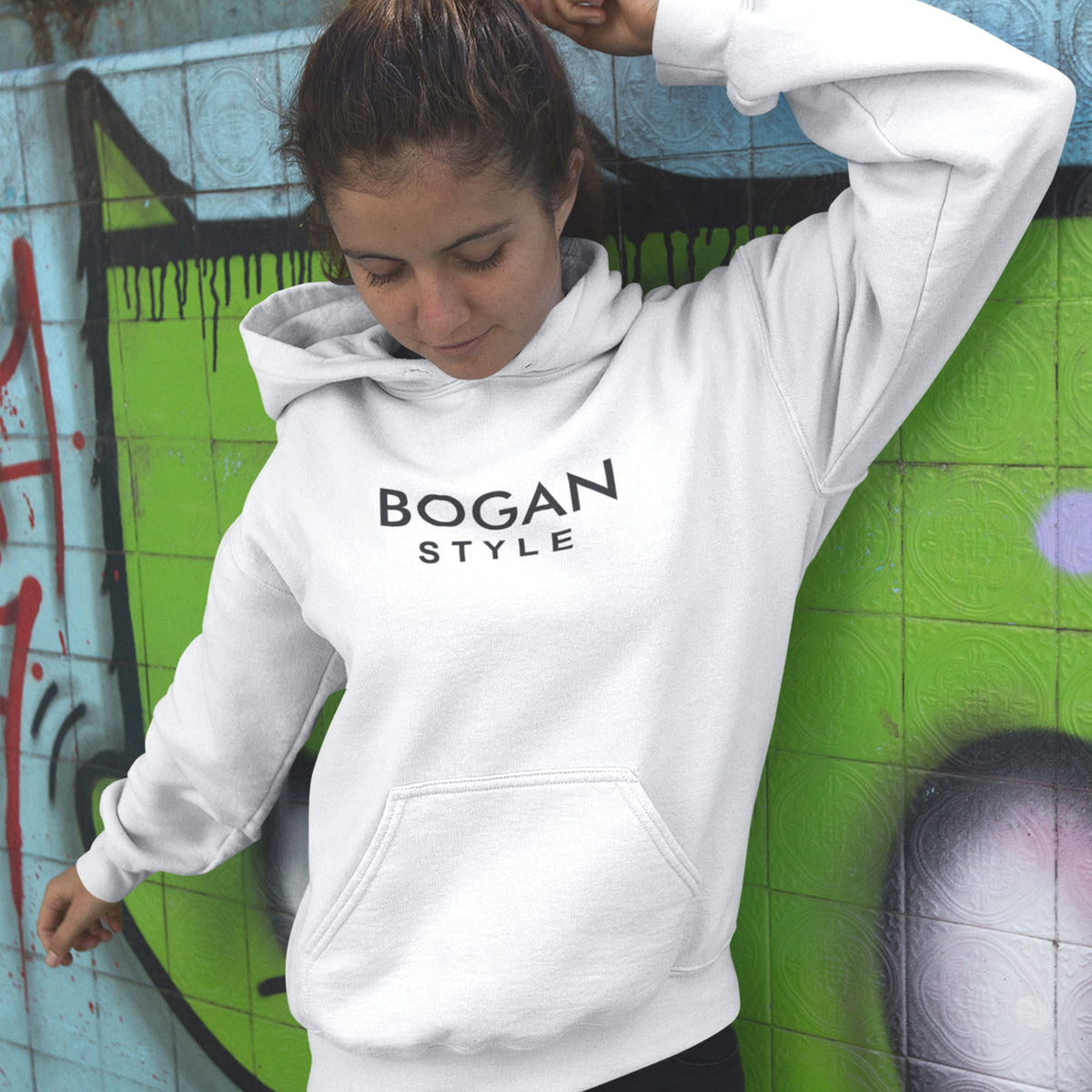 Woman wearing white hoodie standing in front of graffiti wall