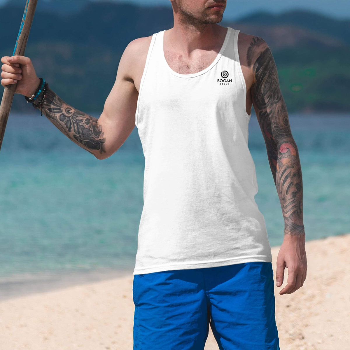 man-on-beach-wears-white-tank-top-with-small-bogan-style-logo