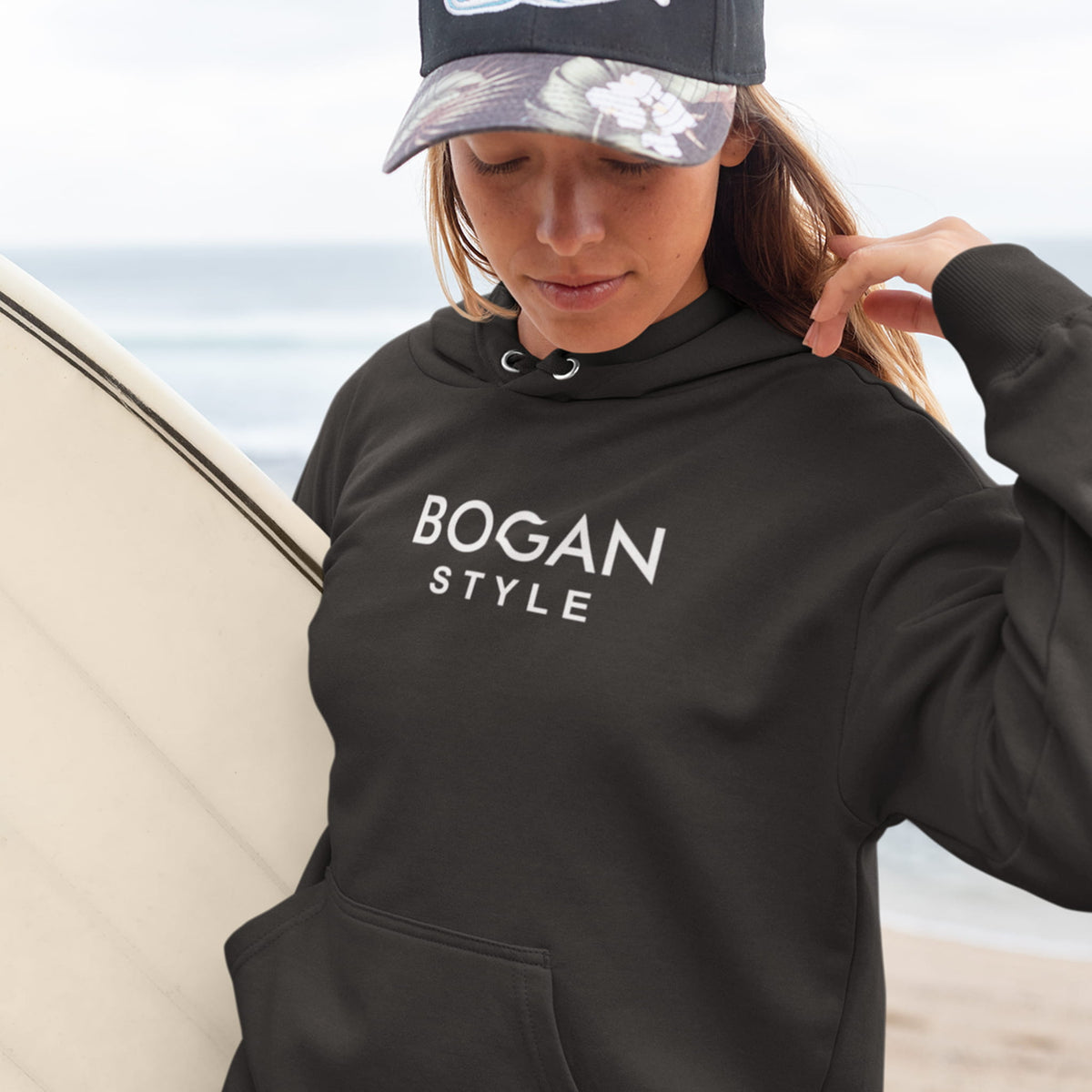 female wears black hoodie to beach with Bogan Style printed on front